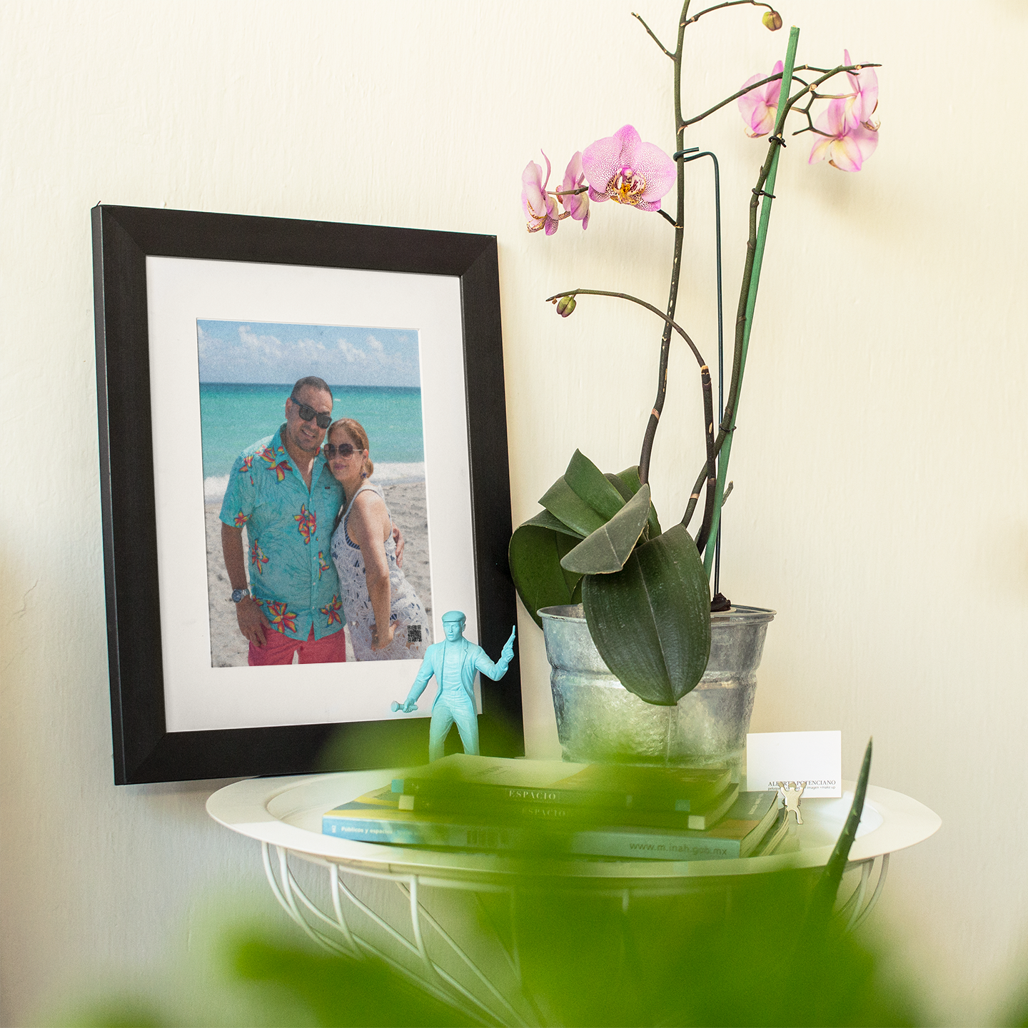 Framed voice message photo of a couple on a beach with an orchid plant on a table.