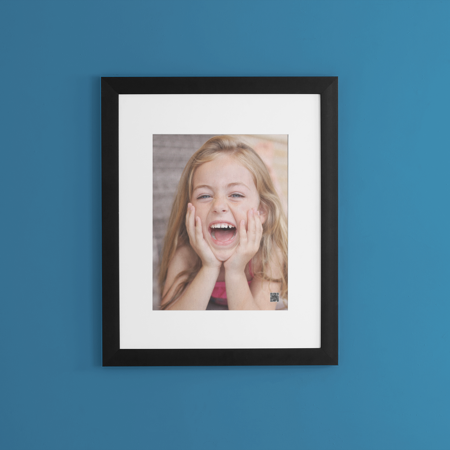 Framed photo of a laughing girl on a blue wall with personalized voice message.