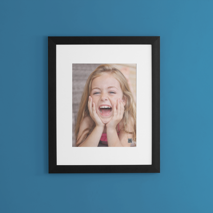 Framed photo of a laughing girl on a blue wall with personalized voice message.