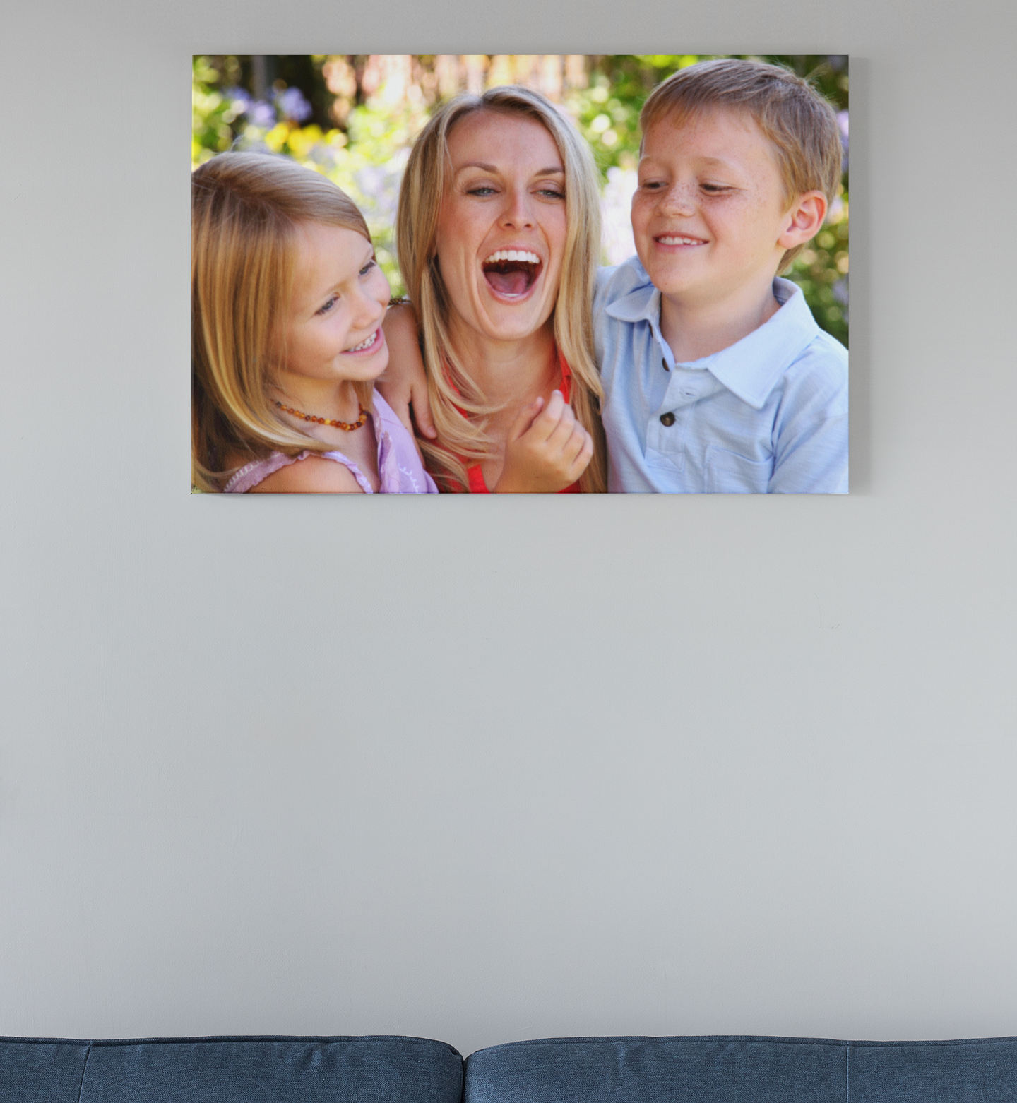 Canvas with audio message of Family photo on a wall above a blue sofa with patterned cushions.
